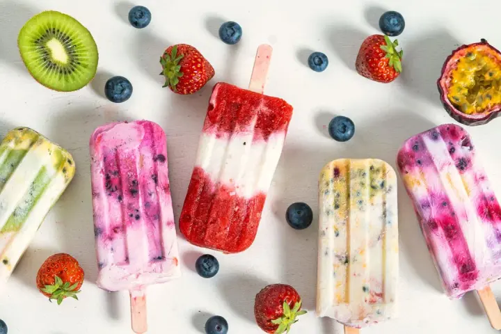 Fruchteis am Stiel mit Beeren, Kiwi und Maracuja. Welches Eis hat am wenigsten Zucker? Die bunten Eis am Stiel sehen lecker aus.
