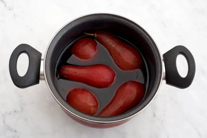 Olla con peras al vino tintas, listas para ser un postre delicioso.