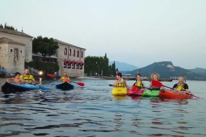 Persone in kayak sul lago verde, con un antico edificio sullo sfondo, vicino a San Vigilio di Marebbe.