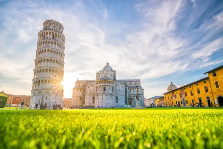 Torre di Pisa e Duomo, tra i più bei posti da visitare in Toscana, con un prato verde brillante e cielo azzurro.