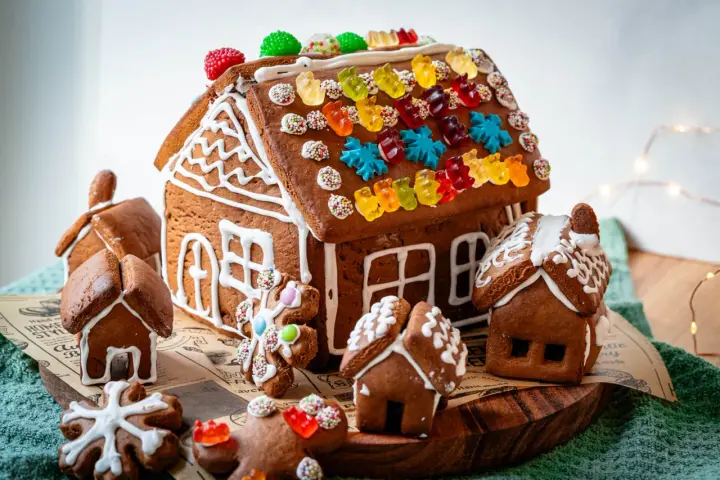 Kreative Ideen für ein Lebkuchenhaus: Ein detailreiches Lebkuchenhaus mit bunten Gummibärchen und kleinen Lebkuchenhäusern drumherum.