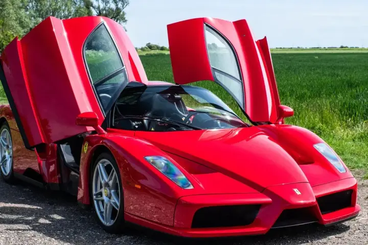 Czerwone Ferrari Enzo z otwartymi drzwiami, marzenie wielu. Zastanawiasz się, ferrari enzo ile kosztuje?
