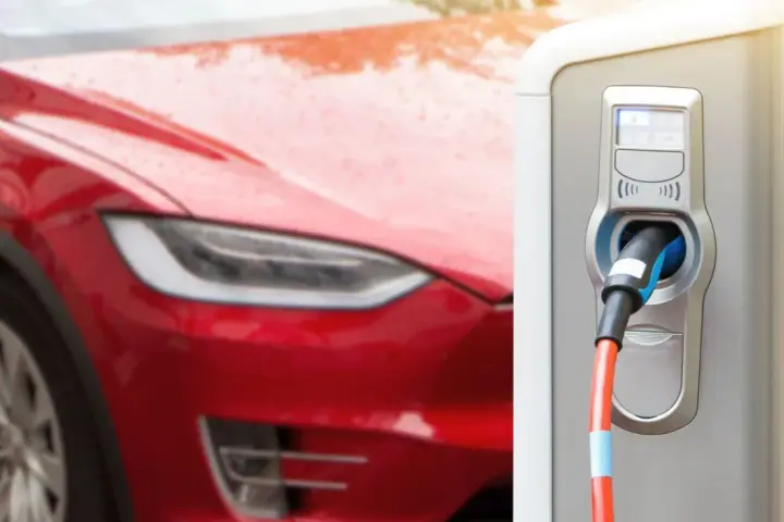 Czerwona Tesla podłączona do ładowarki elektrycznej.