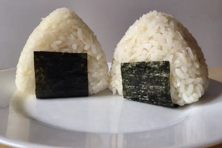 Dwa ryżowe onigiri z nori, gotowe do spożycia. Idealne nadzienie do onigiri sprawia, że są pyszne.