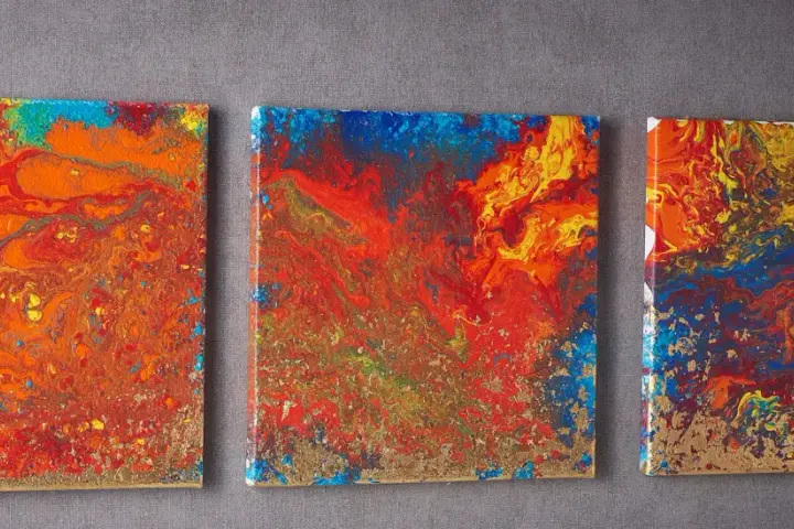 Trois toiles abstraites aux couleurs vives, un exemple de pouring art, avec des touches dorées.