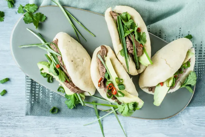 Délicieux bao buns garnis de bœuf, avocat, coriandre et oignons verts. Une recette facile pour un repas savoureux.