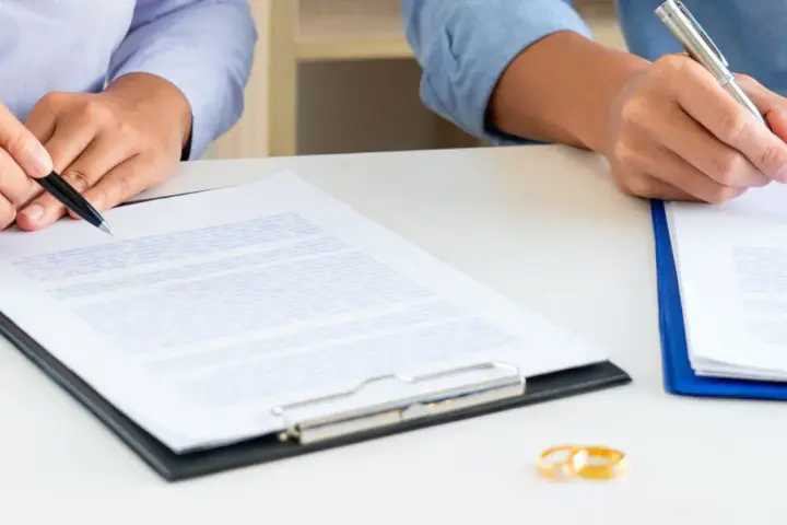 Deux mains signent des documents, symbolisant la fin d'une union. Attention au délai pour réclamer une prestation compensatoire.