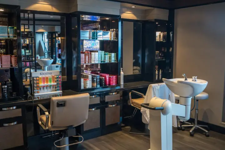 Salon fryzjerski gotowy na klientów. Widać fotele, umywalki i półki z kosmetykami. Dbałość o dezynfekcję w salonie fryzjerskim to podstawa.