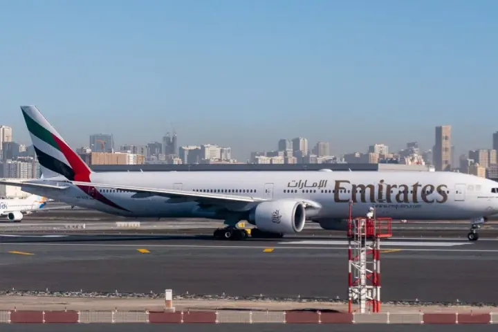 Samolot Emirates na płycie lotniska, w tle panorama Dubaju. Zastanawiasz się, ile się leci do Dubaju?