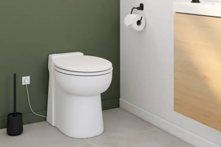 Toilettes modernes avec un sanibroyeur discret, dont le fonctionnement est assuré par une prise électrique visible.
