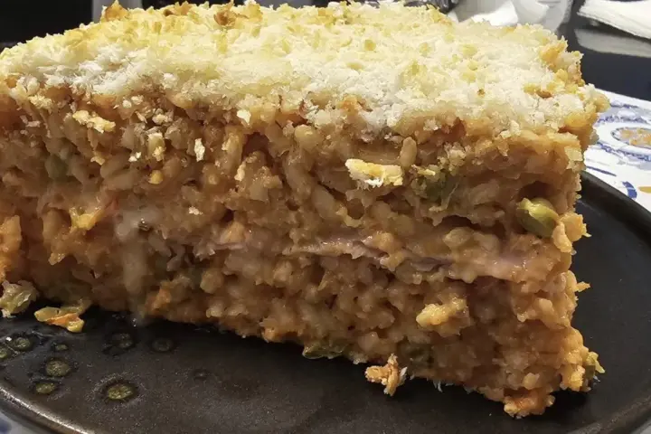 Una fetta di riso al forno, stratificato e dorato, con una crosta croccante di pangrattato.