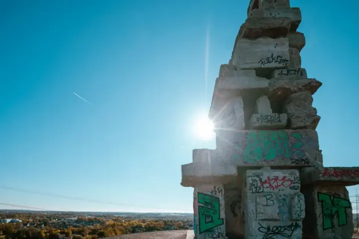 Sonnenstrahlen brechen durch eine Betonkonstruktion auf der Halde Rheinelbe, die mit Graffiti übersät ist.