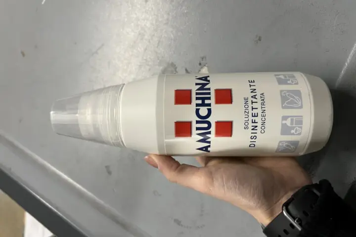 Mano tiene flacone Amuchina per disinfettare ciuccio. Soluzione disinfettante concentrata per igiene.