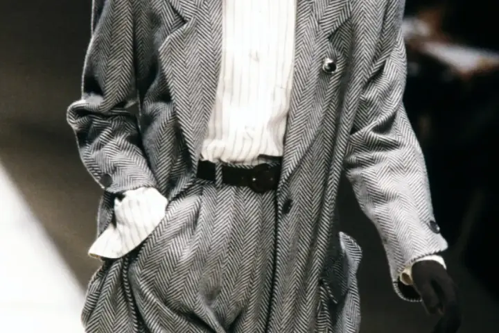 Un elegante power suit de espiga gris con camisa a rayas y cinturón negro.