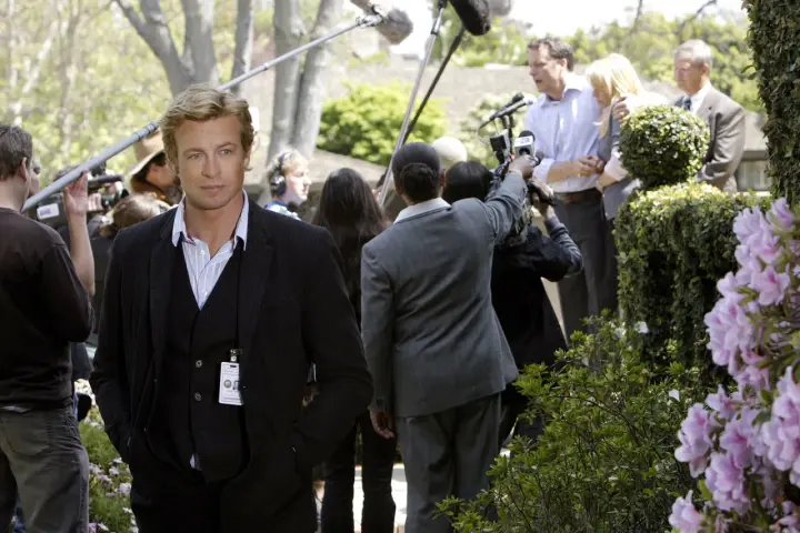 Simon Baker, con la sua nuova fidanzata, è circondato da telecamere e microfoni durante un evento all'aperto.