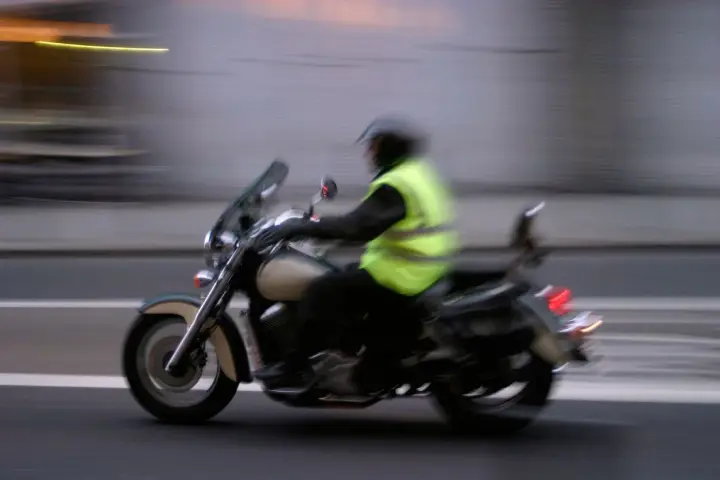 Motociclista con chaleco reflectante amarillo brillante, cumpliendo la norma de que es obligatorio llevar chaleco reflectante en la moto.