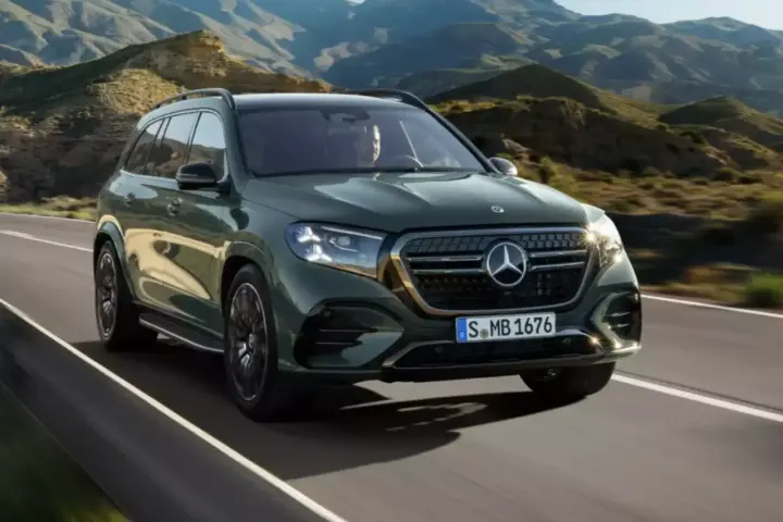 Zielony Mercedes GLS 580 pędzi po krętej drodze wśród gór.