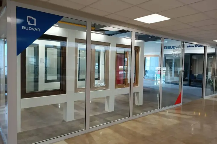 Salon okien i drzwi z ekspozycją okien i drzwi. Logo Budvar.