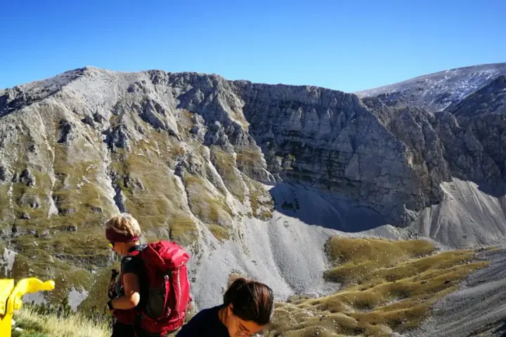 Escursionisti con zaini rossi ammirano il panorama montuoso vicino al bivacco Fusco.