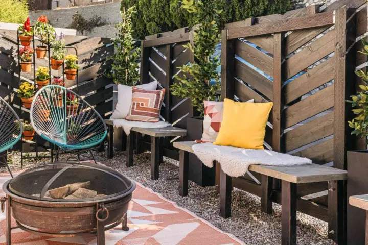 A cozy patio with a diy privacy screen, fire pit, and colorful chairs.