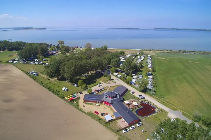 Luftaufnahme des pepelow campingplatzes mit Wohnmobilen, Bäumen und einem See im Hintergrund.