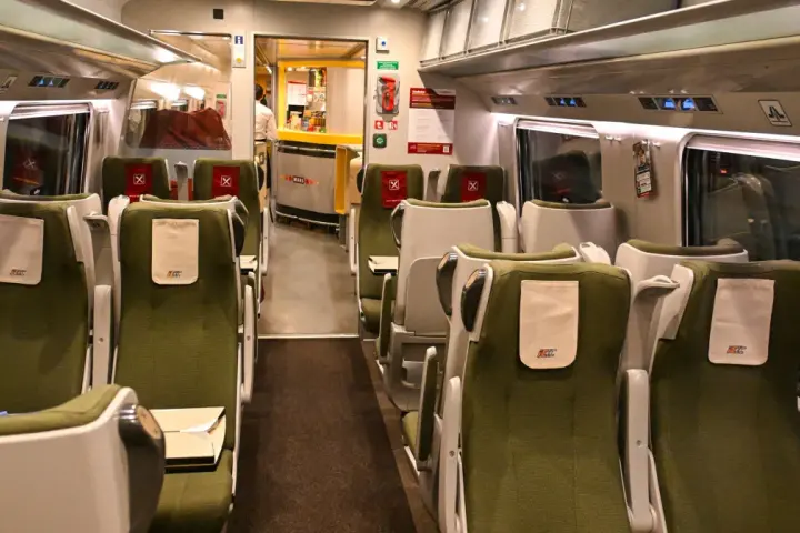 Wnętrze wagonu PKP Intercity IC 4520 Hutnik. Rozkład miejsc w zielonych fotelach, z widocznym barem Wars.