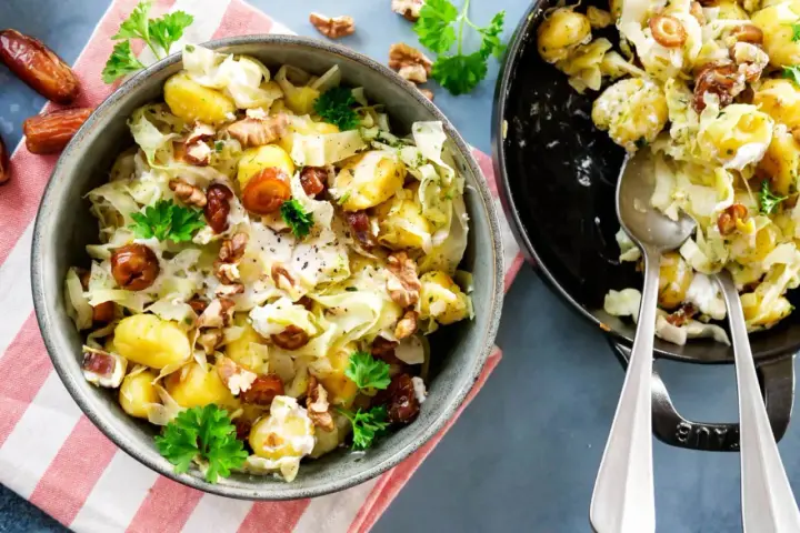 Leckeres rezept mit spitzkohl, Kartoffeln, Datteln und Walnüssen in cremiger Soße, garniert mit Petersilie.