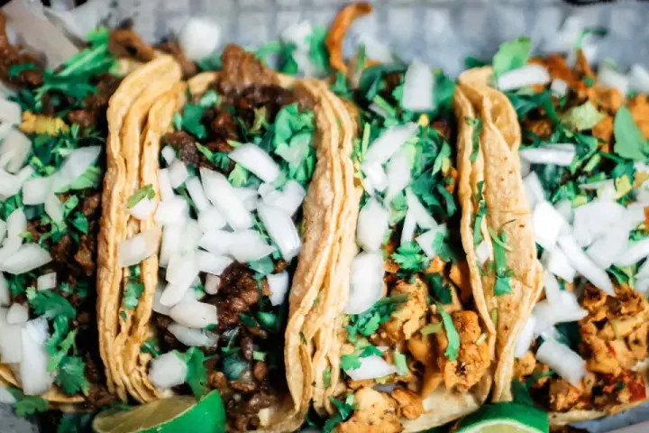 Fünf köstliche Tacos mit Rindfleisch und Hähnchen, garniert mit Zwiebeln und Koriander. Perfekt für einen Taco-Abend!