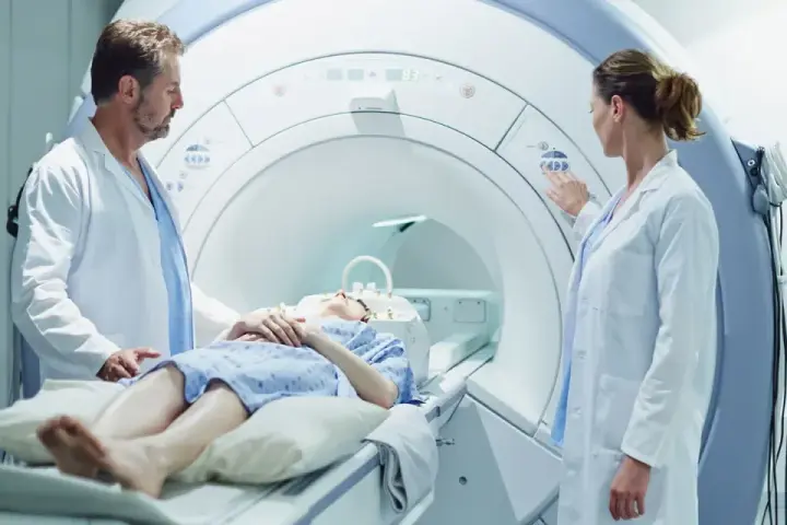 Pacjentka leży w skanerze MRI, podczas gdy lekarze przygotowują badanie. To właśnie mri co to za badanie, które pozwala zajrzeć do wnętrza ciała.