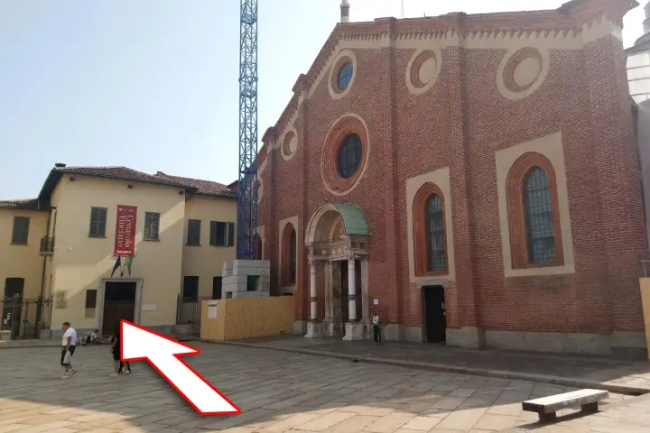 Plac przed kościołem z banerem "Cenacolo Vinciano". Bilety na Ostatnią Wieczerzę można kupić w pobliżu.