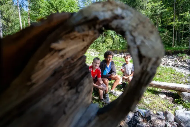 Trois enfants profitent d'une pause en forêt, rappelant l'importance du respect des locaux et de la nature.