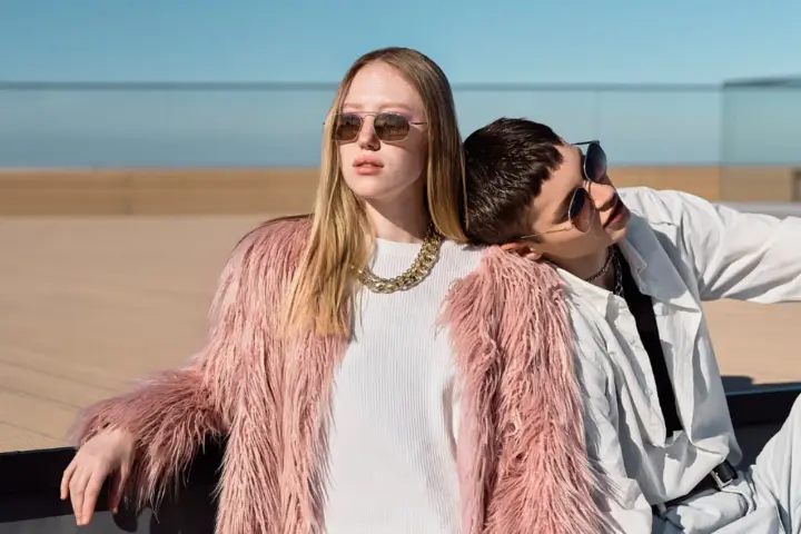 Chica con abrigo rosa peludo y collar dorado, apoyada en un chico con camisa blanca. Inspiración para como ser una chica aesthetic.