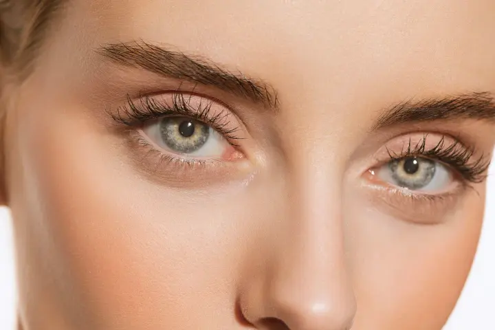 Maquillage subtil pour paupières tombantes, rehaussé par le regard intense derrière des lunettes imaginaires.