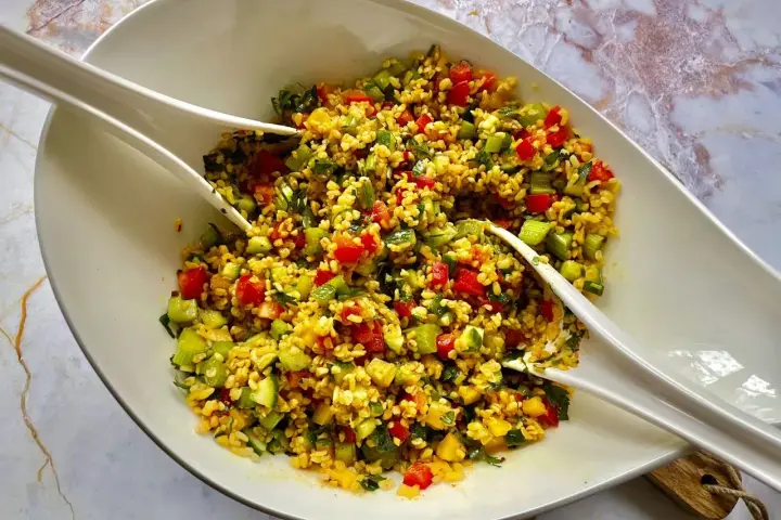 Kolorowa sałatka z kaszą bulgur, pomidorami, ogórkiem i ziołami, gotowa do podania.