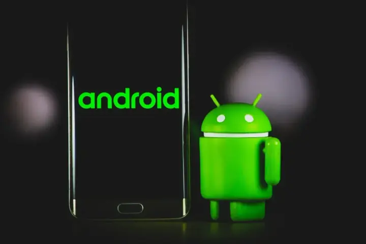 Zielony robot Android obok telefonu z logo Android 13.
