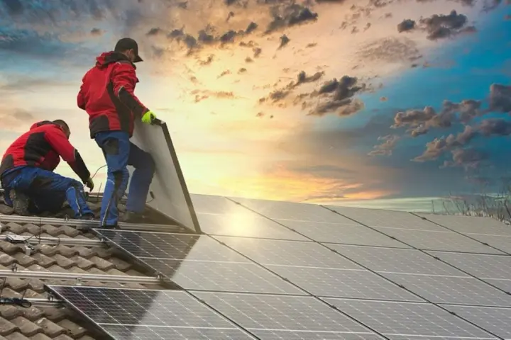 Instalatorzy montują panele fotowoltaiczne, by zapewnić maksymalną wydajność i czystą energię. Zachód słońca dodaje uroku.