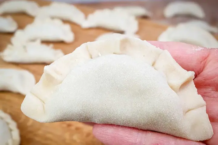 Gotowe do lepienia pierogi na desce. Idealne ciasto na pierogi, jak u Magdy Gessler, czeka na nadzienie.