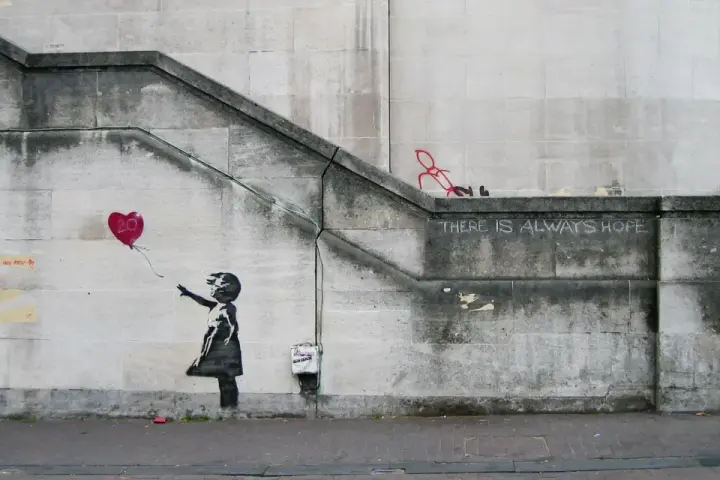La célèbre œuvre de Banksy, "Girl with Balloon", sur un mur de pierre. Une petite fille lâche un ballon en forme de cœur rouge.