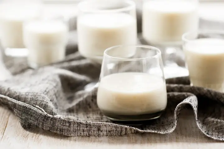 Plusieurs verres remplis de kéfir crémeux, posés sur une serviette grise.