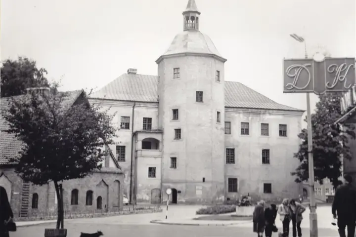 Zamek książąt pomorskich w Słupsku, z charakterystyczną wieżą i arkadowym balkonem, na tle miejskiego krajobrazu.