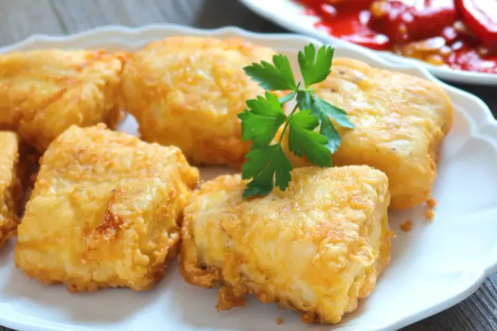 Crujientes trozos de merluza a la romana, dorados y listos para disfrutar. Un clásico plato español.