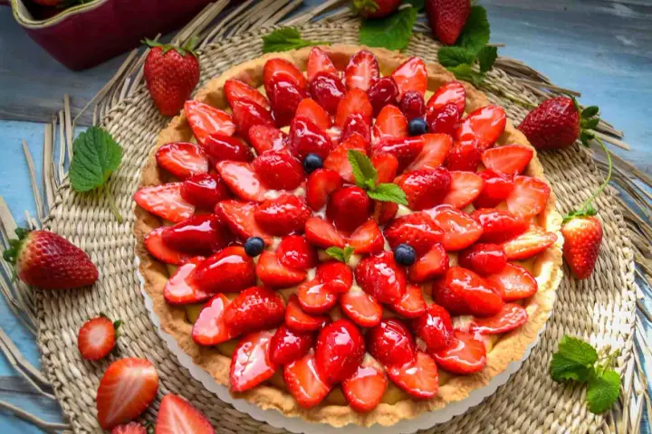 Ein leckerer Erdbeerkuchen mit einem wunderschönen Muster aus frischen Erdbeeren und Blaubeeren, glasiert und garniert mit Minze.