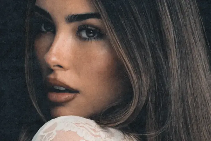 Zbliżenie na twarz Madison Beer, zmysłowe spojrzenie i delikatny uśmiech. Fani Madison Beer Polska czekają na jej powrót.