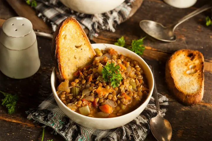 Zuppa di lenticchie ricca e saporita, servita con pane tostato e prezzemolo fresco. Un classico tra le ricette con lenticchie.