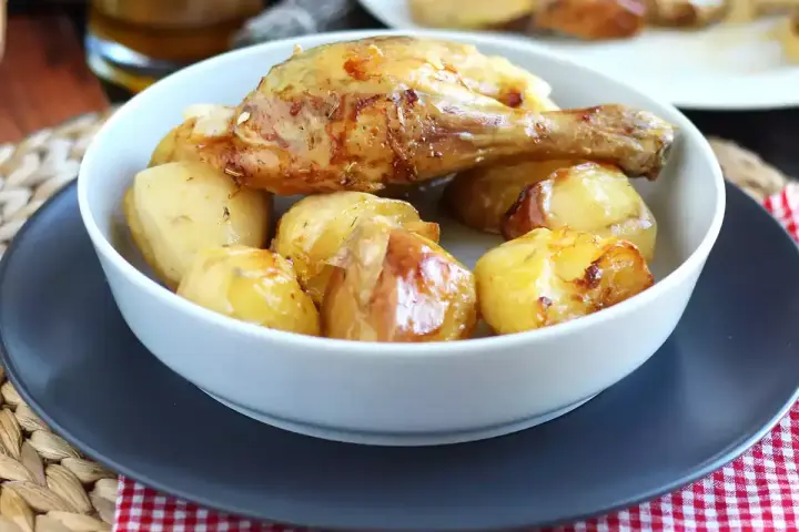 Un invitante pollo al forno con patate dorate, un classico piatto che profuma di casa.