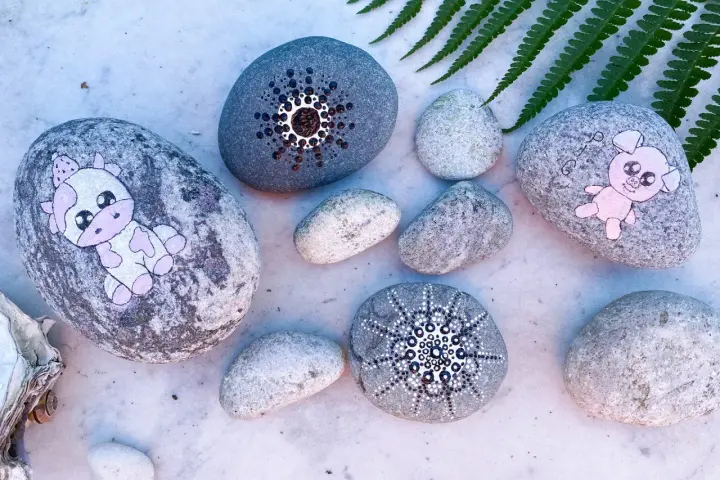 Söta djur på stenar: en ko med prickar och en rosa gris. Måla djur på sten är en rolig hobby.