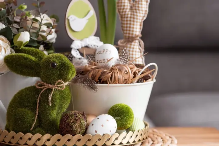 Zielony, mchowy zajączek i pisanki tworzą najpiękniejsze dekoracje wielkanocne. W koszyku jajko z napisem "Happy Easter".