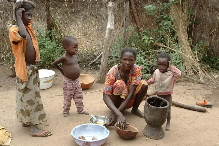 Dzieci i matka w tradycyjnej chacie w Burkina Faso. Kobieta przygotowuje posiłek, a dzieci obserwują.
