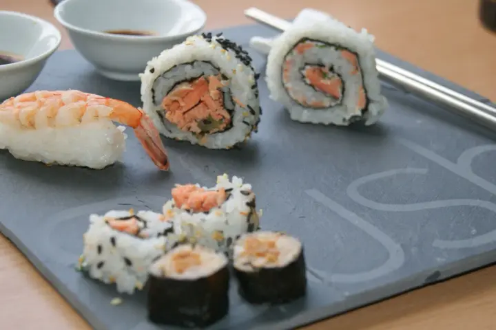 Jak przygotować krewetki do sushi? Na talerzu sushi z krewetką i rolkami z łososiem.