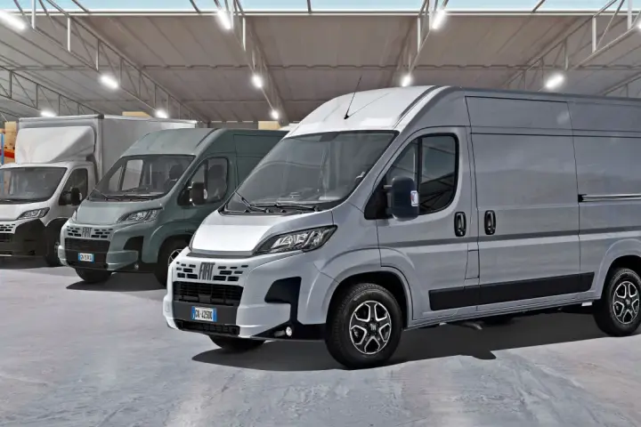 Rząd szarych furgonetek Fiat Ducato Maxi w magazynie z półkami i pudełkami.